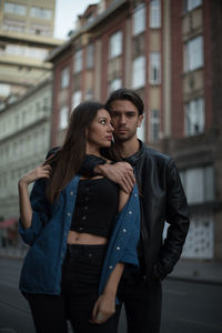 Happy young woman with arms raised standing in city