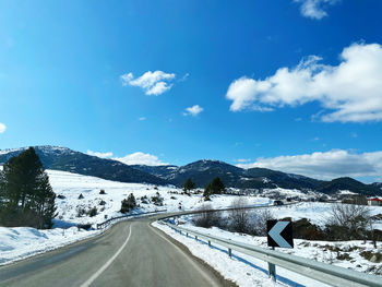 Road amidst snowcapped mountains against sky during winter