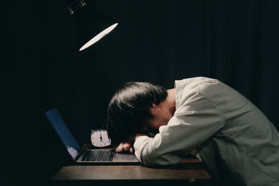 Men sleep on the study table. laptop turns on in front of it.