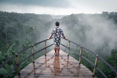 Rear view of man standing on footbridge