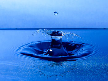 Close-up of drop falling on blue water