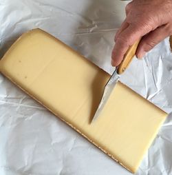 High angle view of hand cutting cheese