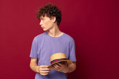 Young man wearing hat against red background