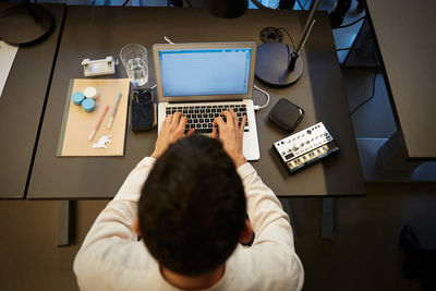 High angle view of businessman using laptop at desk in creative office