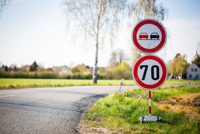 Road sign on field against sky