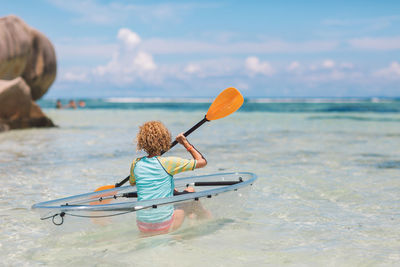 Rear view of girl kayaking in sea