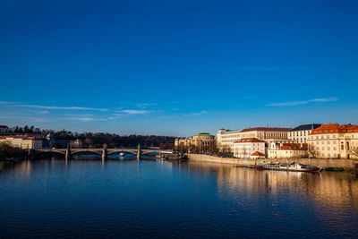 City at waterfront against blue sky