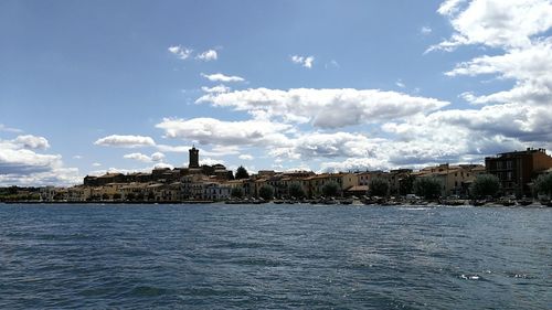 Scenic view of river by cityscape against sky