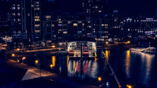 High angle view of illuminated buildings by river at night