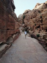 Man walking on cliff against clear sky