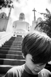Boy on staircase against temple and sky