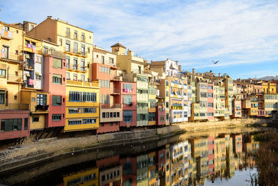 Buildings by river against sky in city