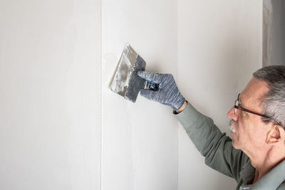 Adult man makes even and putty the corners in his house with special mixture. home renovation, diy. 
