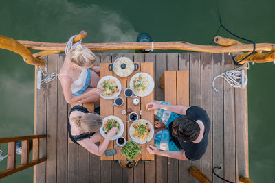 Directly above shot of people having lunch on wooden pier by lake