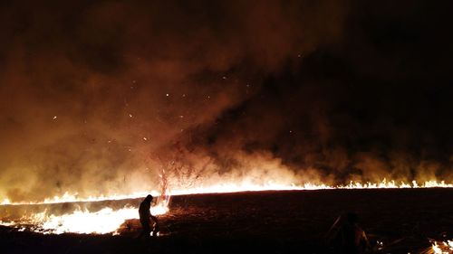 Man sitting on burning field at night