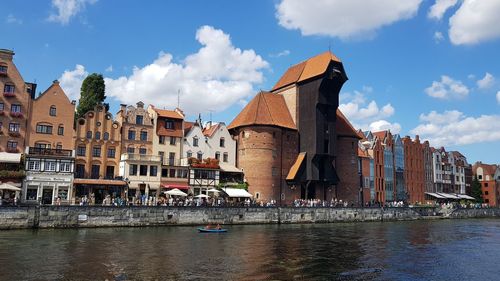 Buildings by river against sky in city