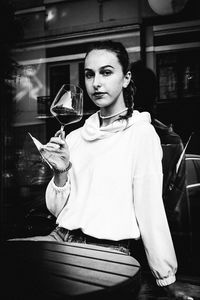 Portrait of young woman drinking glass in restaurant