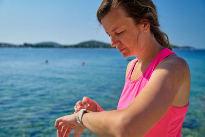 Side view of young woman looking at sea against clear sky