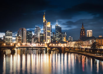 Illuminated bridge over river in city at night