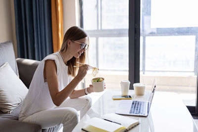 Woman using phone while sitting on table