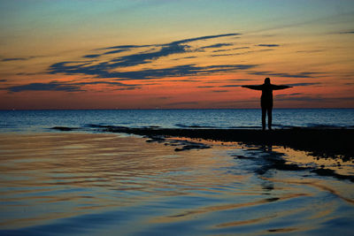 Silhouette person standing on beach against sky during sunset