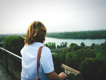 Rear view of woman standing by railing against sky