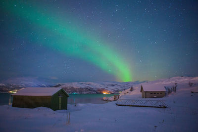 Houses on snow against sky during winter at night