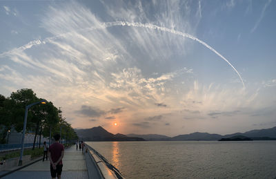 Rear view of people on mountain against sky during sunset