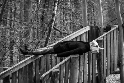 Man skateboarding on tree trunk in forest