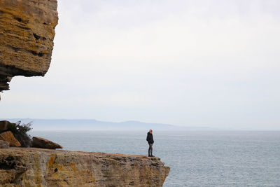 Man by himself in steep rugged orange cliffs at lands end in eastern australia