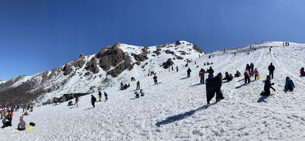 Group of people on snowcapped mountain against sky