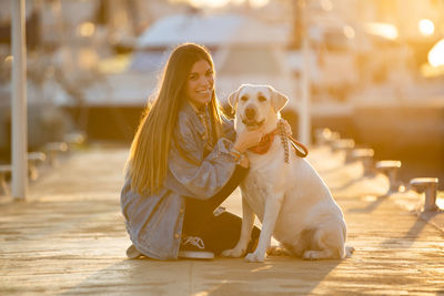 Portrait of woman with dog at harbor during sunset