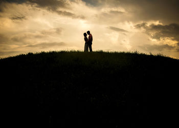 Silhouette man standing on field against sky during sunset