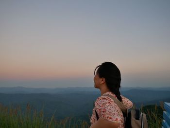 Woman looking at mountains against sky during sunset