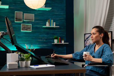 Young woman using mobile phone at table