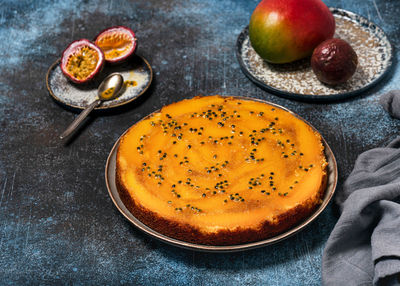 Homemade whole mango upside down cake with passion fruit on a dark rustic background