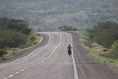Rear view of woman on road along landscape