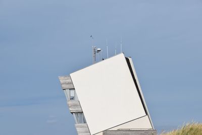 Low angle view of building with communications tower against clear sky