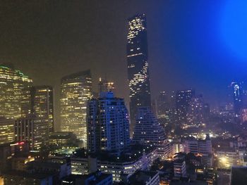 Illuminated buildings in city against sky at night