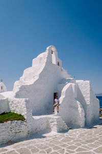 People on white wall against clear blue sky