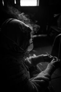 Side view of person wearing oxygen mask sitting in darkroom