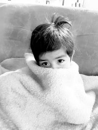 Portrait of cute boy wrapped in blanket at home