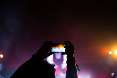 High section of man photographing concert at night