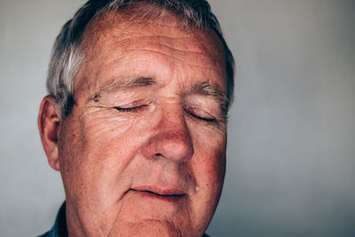 Close-up of man with closed eyes against wall