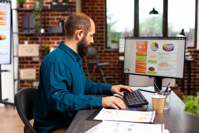 Side view of man using laptop at table