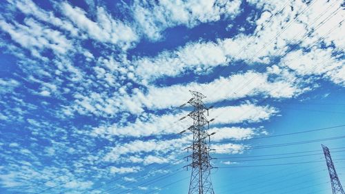 Low angle view of electricity pylon against cloudy sky