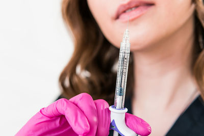 Midsection of woman holding syringe against white background