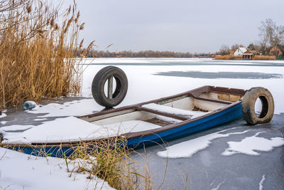 Snow covered field by lake against sky