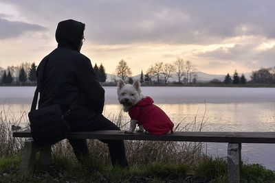 Man with dog on lake against sky