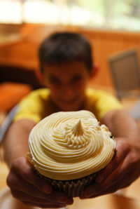 Smiling boy showing cupcake at home